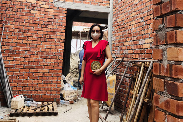 Master Suyen Lim holding a luopan compass inside a brick house under construction