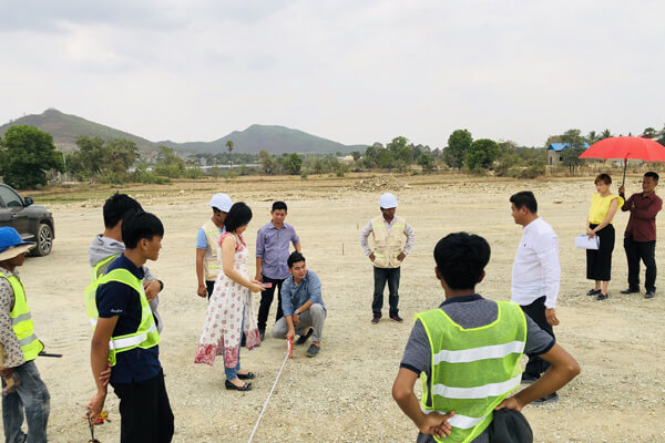 A land survey in progress, a measuring tape stretched across a cleared plot