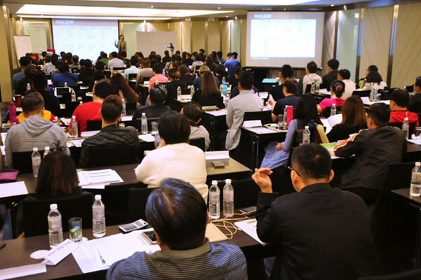 A full training room working through charts on two projector screens