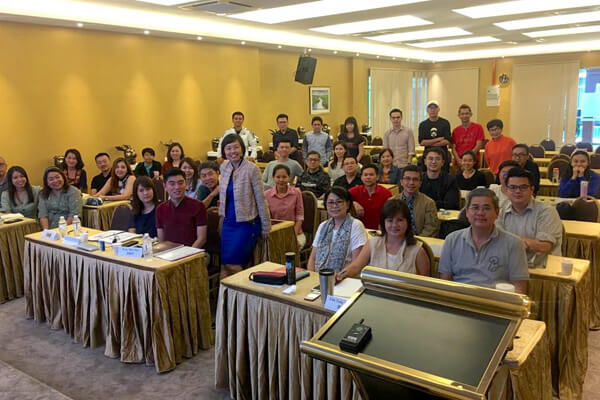 Master Suyen Lim standing with a class of students in a seminar room