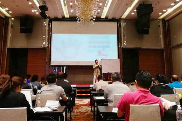 Master Suyen Lim teaching beside a flip chart in a function room