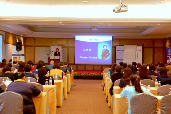 An audience seated for a talk, the screen introducing Master Suyen Lim