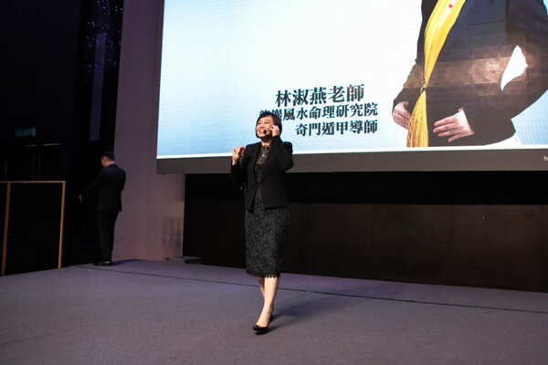 Master Suyen Lim on stage, the screen behind showing her name and title
